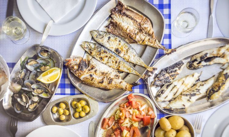Fish feast: sea bass, golden, horse mackerel accompanied with tomato salad, clams, bread and white wine, Portugal