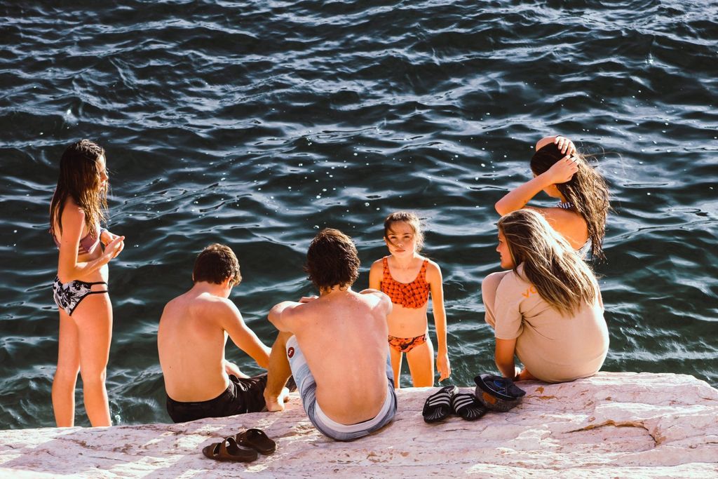 Group of kids sitting on rocks by the sea