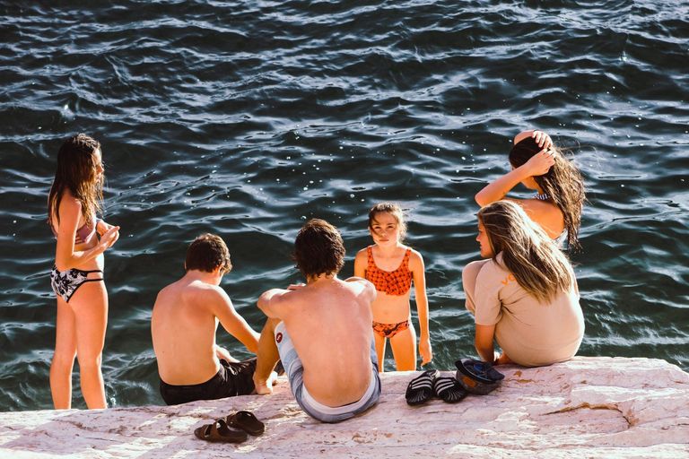 Group of kids sitting on rocks by the sea