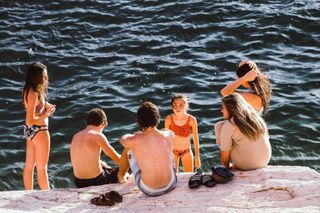 Group of kids sitting on rocks by the sea