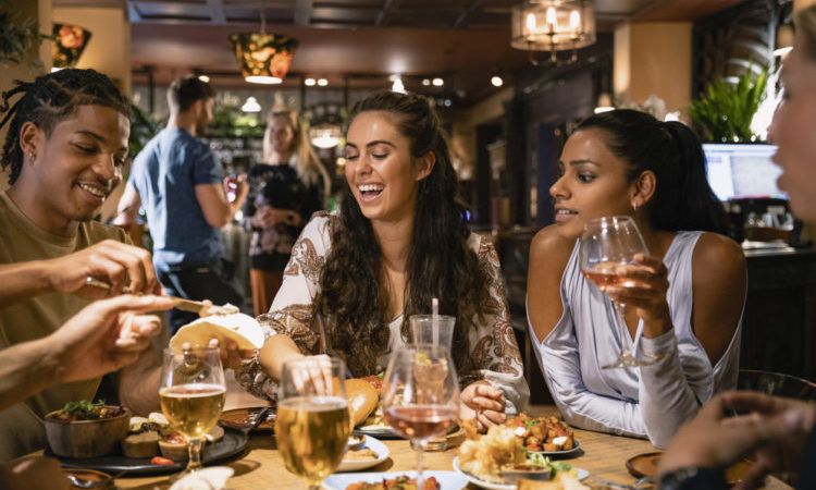 A mixed age range group of friends having a meal together at a restaurant.
