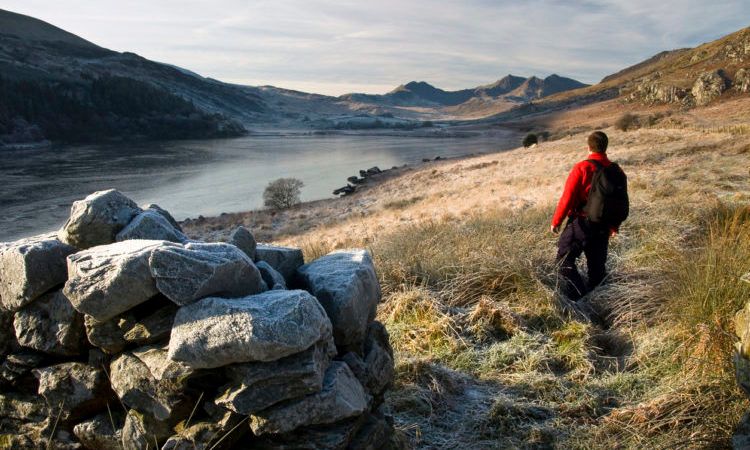 man on a walk, looking out to the view of a lake in snowdonia national park in wales