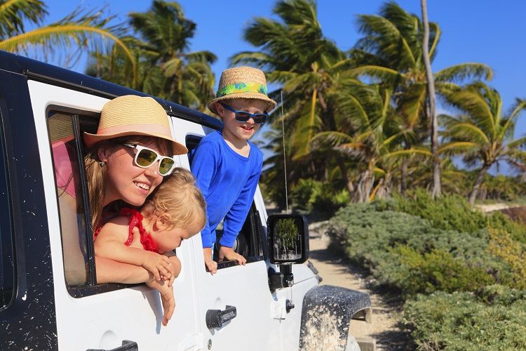 family driving off-road car on tropical beach, vacation concept