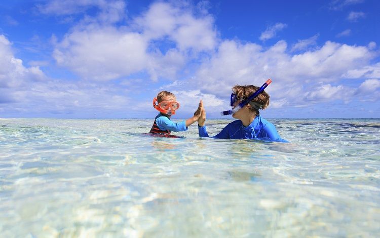 happy mother and son snorkeling on tropical beach