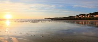 empty beach with a few surfers and dog walkers in the evening, uk