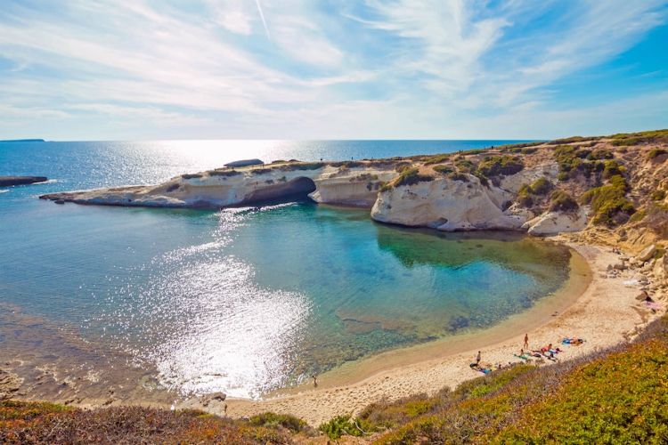 beaches in sardinia | sun reflection in water by sandy beach and limestone cliffs | S’Archittu