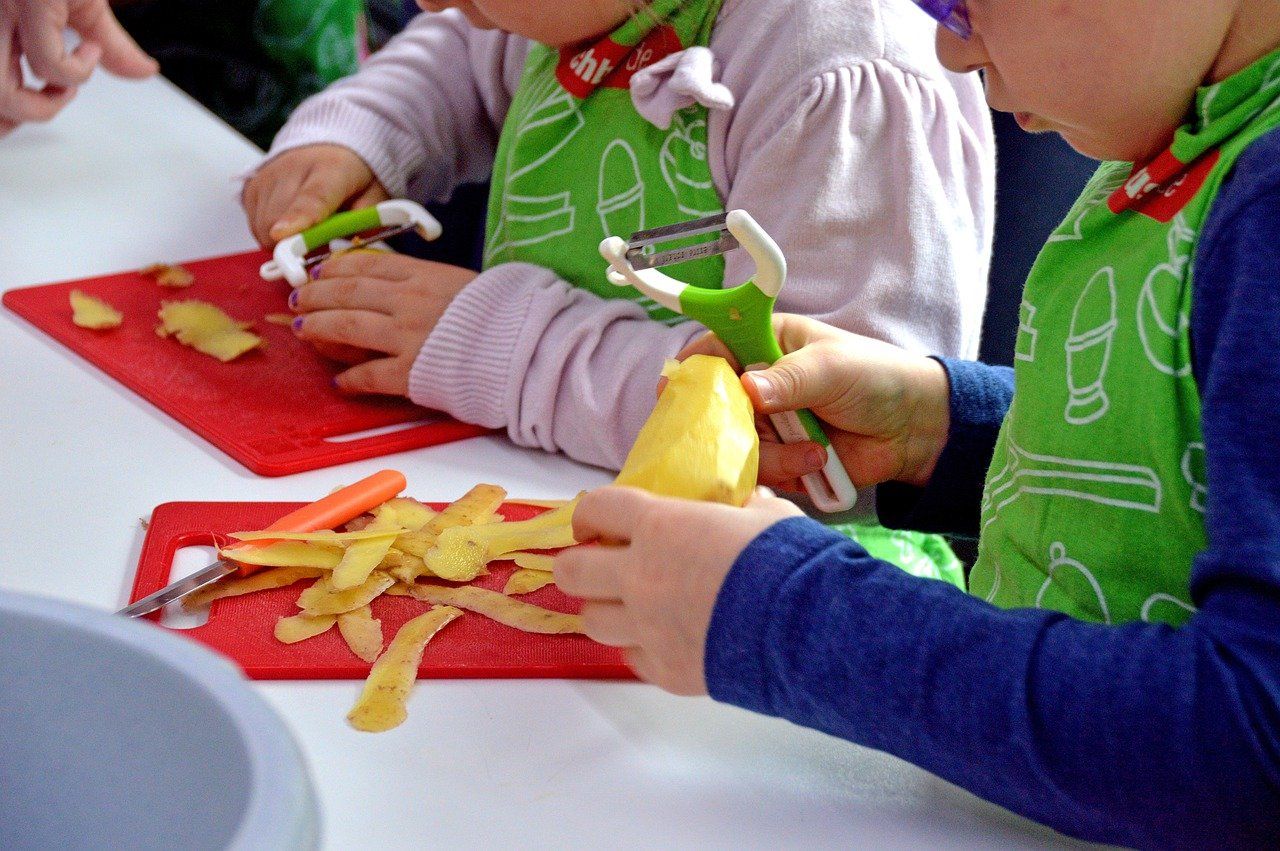 two kids helping parents cook