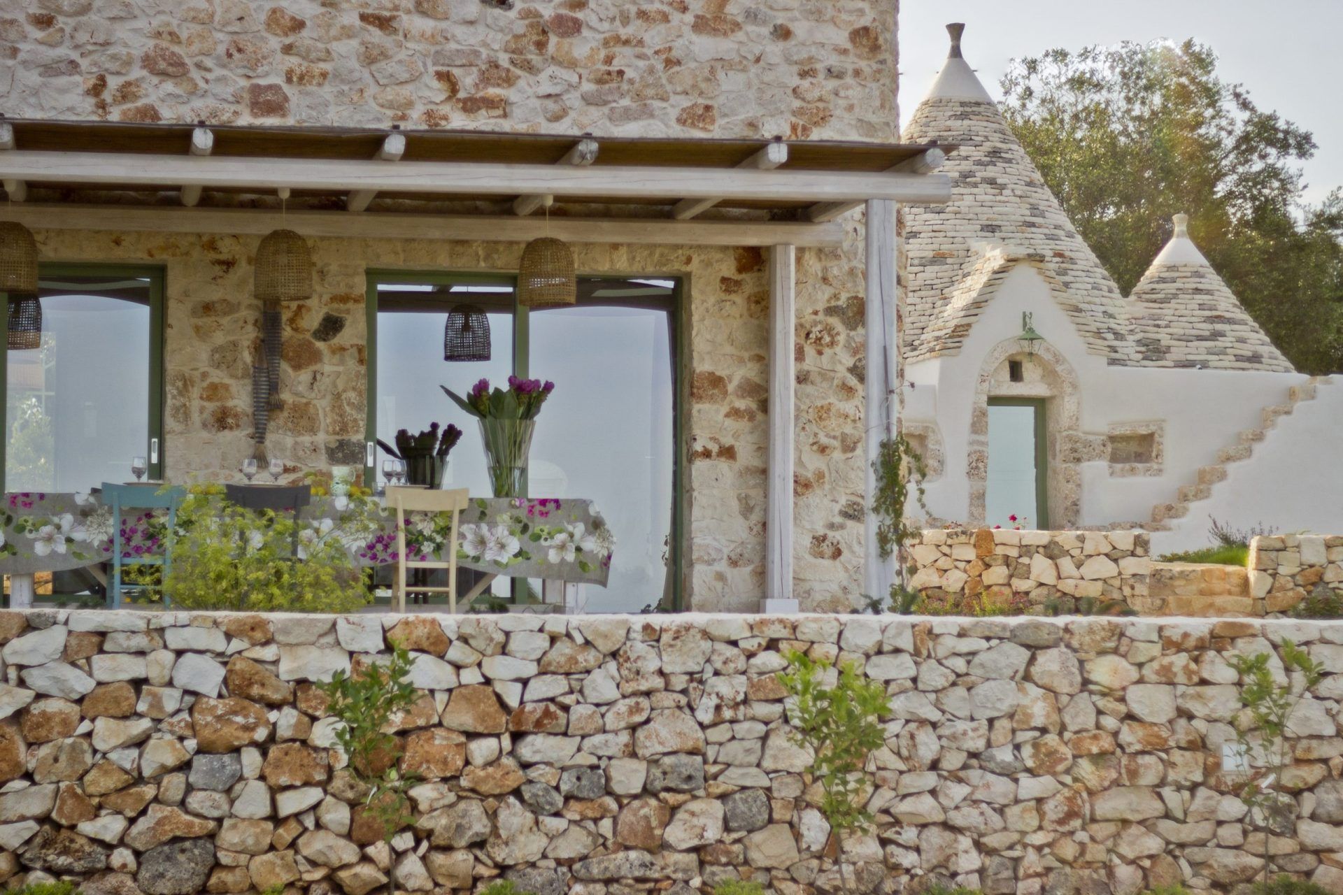 Exterior of cream brick conical trullo house with dinner table
