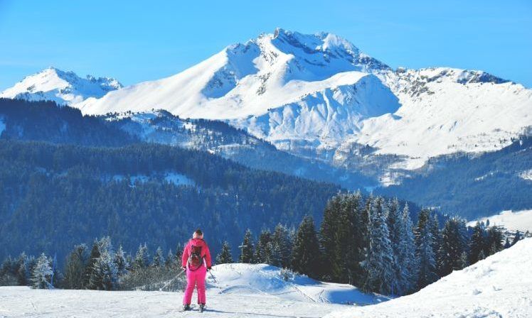 lady in pink ski wear looking out over ski slopes