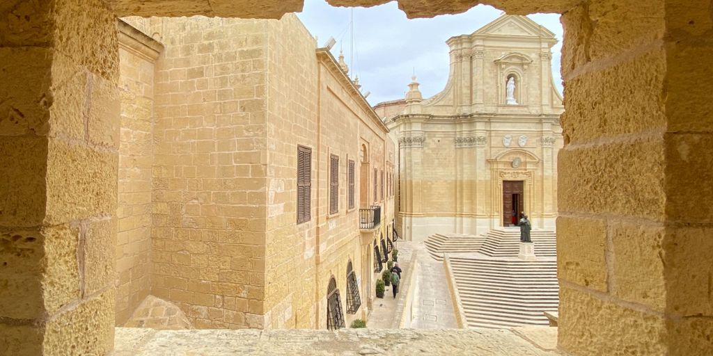 one of the things to do in Gozo: an image of the cathedral through a rocky window