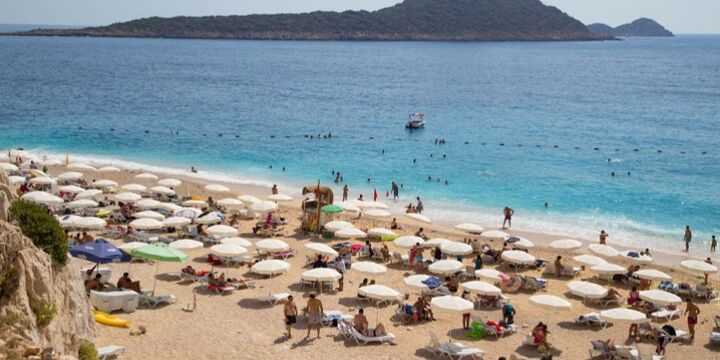 Beach in Kalkan, full of tourists and umbrellas