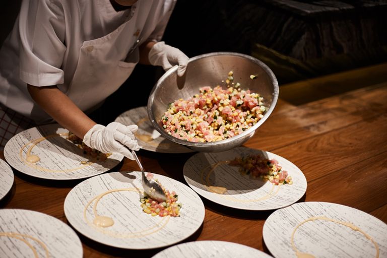 Closeup of professional chef plating dish in restaurant kitchen.